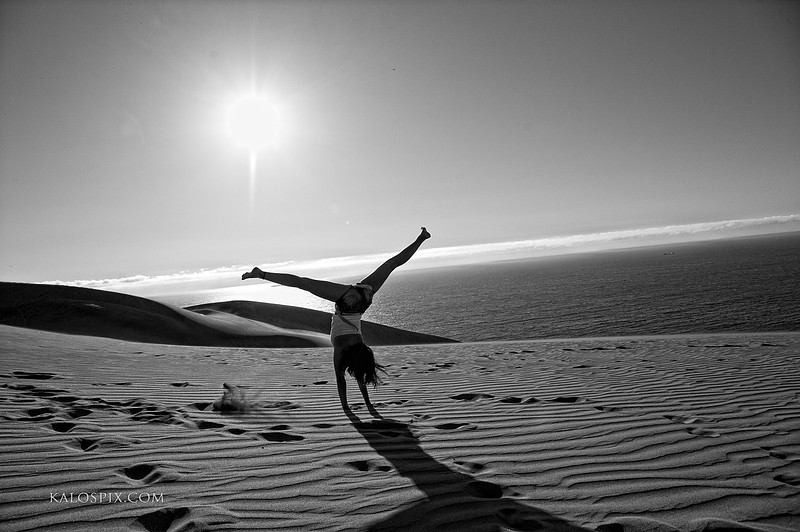 Silhouette cartwheel on a sand dune at sunset, black and white