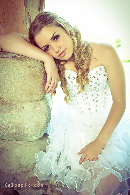 Woman in an elegant white dress, portrait against a stone column
