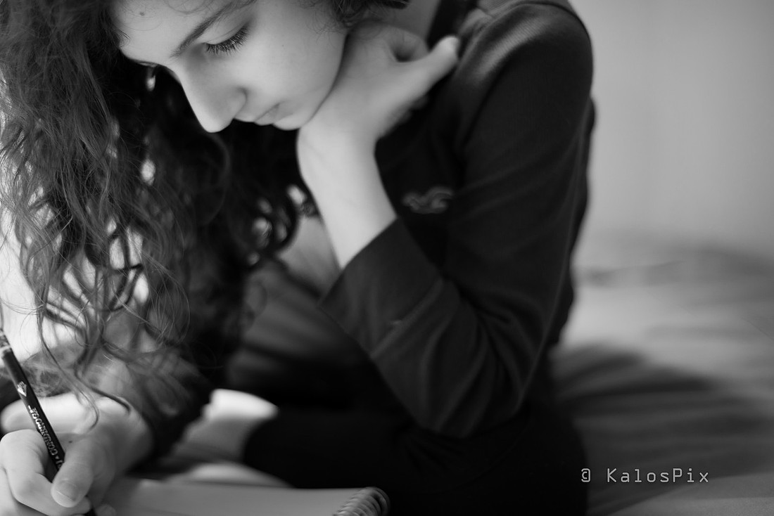 Black and white portrait of a young woman writing, deep in thought